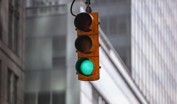 Close-up of green traffic light against blurred city buildings