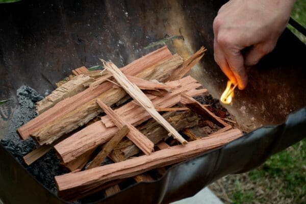 Hand setting wood chops a fire from a match stick