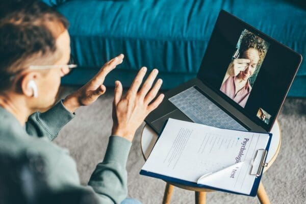 Man holding up hands to calm down woman on video call