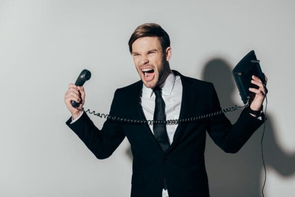 Angry businessman in suit screaming with phone in hands 