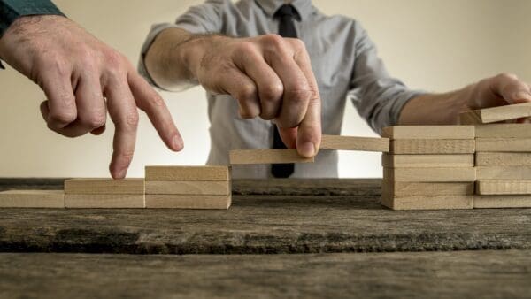 Businessman building a bridge between two staircases 