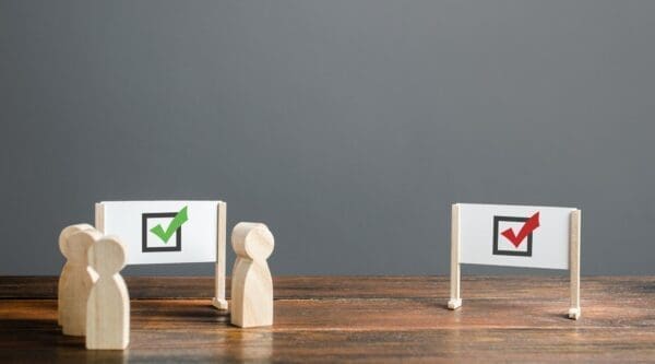 Wooden figures in front of the board with the green tick