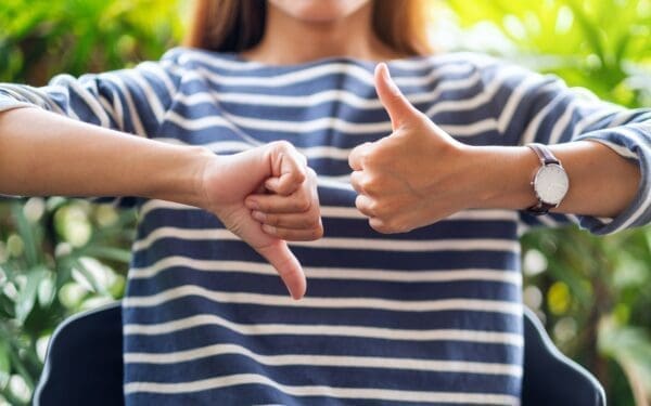 Closeup image of a woman making thumbs up and thumbs down hands sign