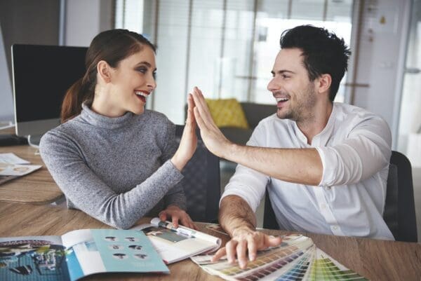 Colleagues sharing a high five over a desk