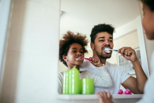 Father and son brushing teeth in a mirror