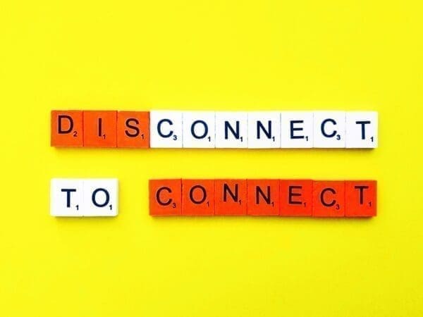 Disconnect to connect Disconnect to connect spelled with word scramble cubes on yellow background