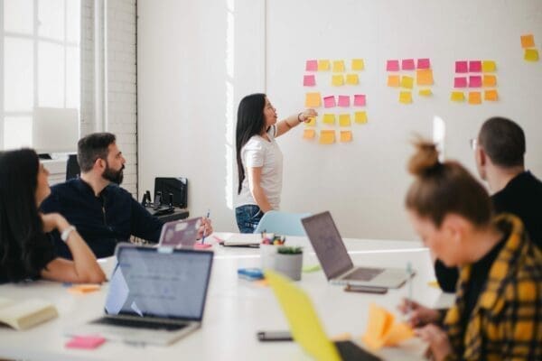 female manager putting sticky notes on whiteboard in board room