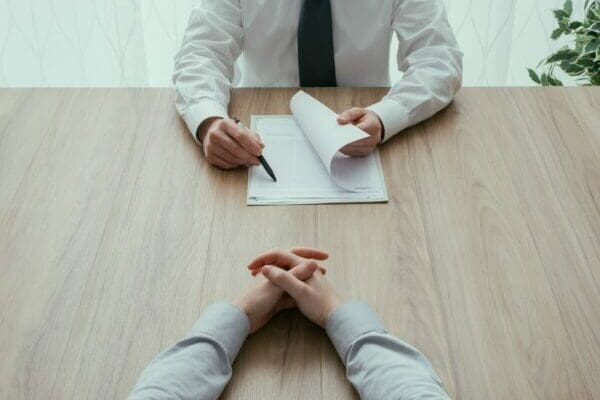 Hands of HR manager and job applicant on a desk during a Job interview