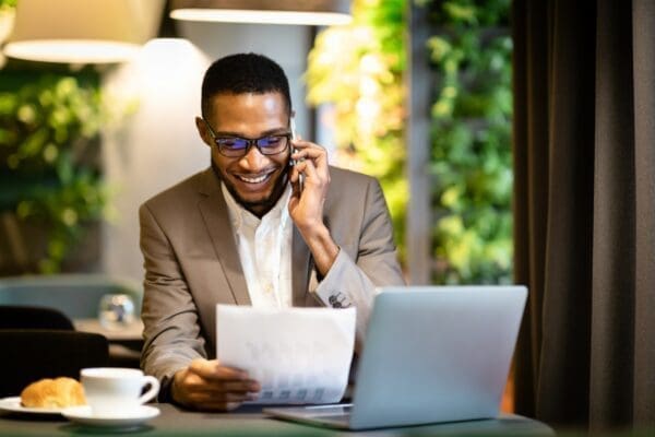 Job applicant doing a phone interview while looking at his resume and using a laptop