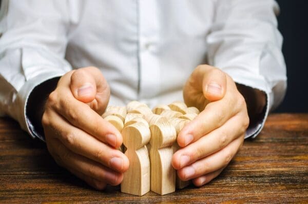 HR hands around a group of wooden figures representing employees