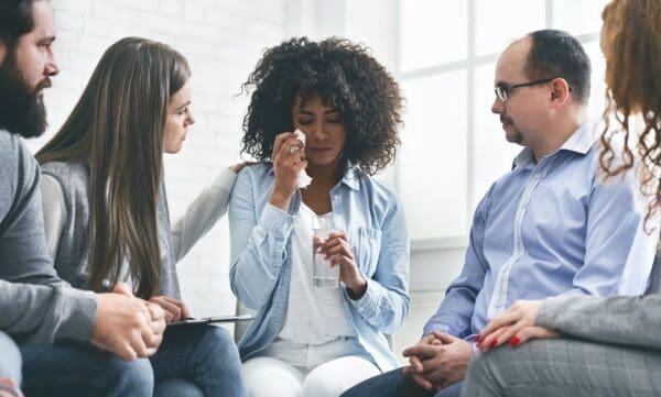 Group of people comforting a crying woman displays compassion in a team