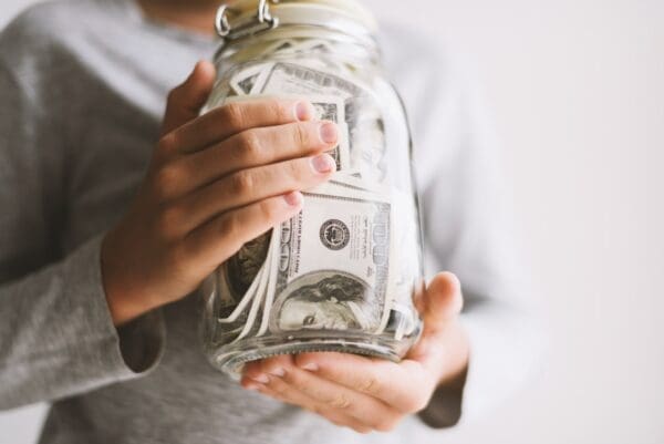 Woman holding glass jar stuffed with money notes represent finance
