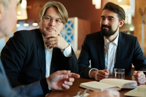 Two businessman intently listening to another man
