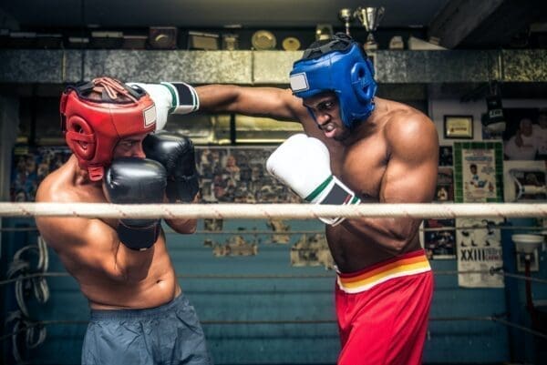 Boxing match between two men wearing red and blue helmets