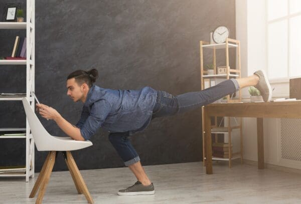 Flexible work-from-home man stretching leg while using a tablet benefits from employee reward system