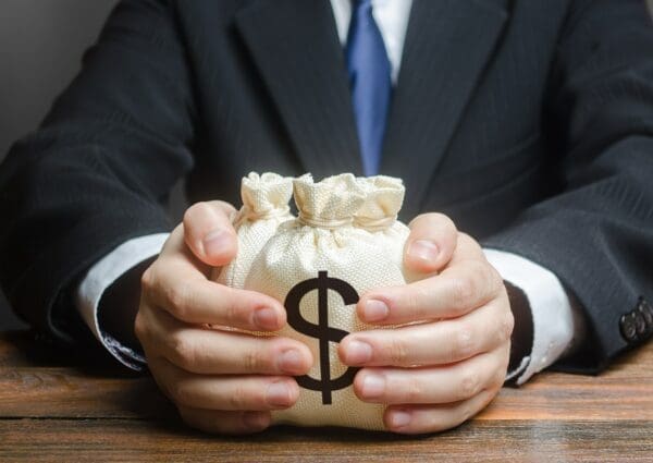 Businessman holding three money bags represents investment