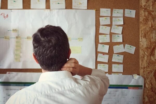 Businessman standing in front of a board with post it notes on is problem-solving