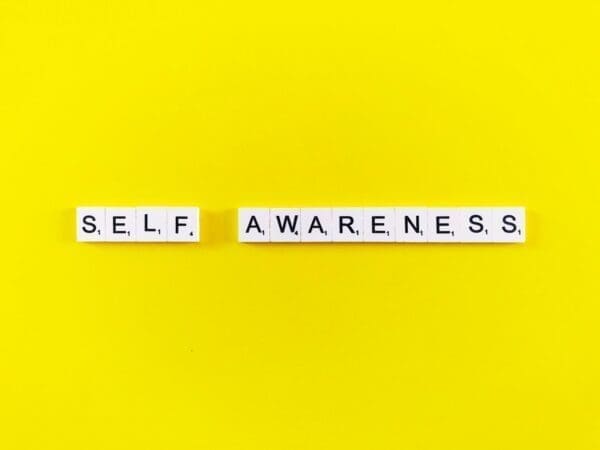 Self-awareness spelled with word scramble cubes on a yellow surface
