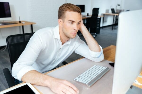 Tired bored young businessman learning from his computer