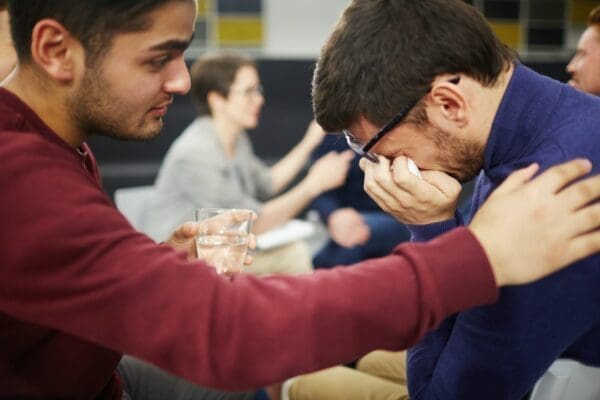 Male coworker comforting a crying male coworker