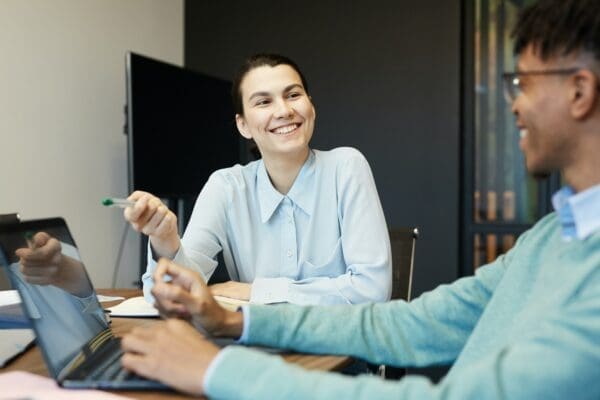 Two colleagues at a desk looking happy and building rapport