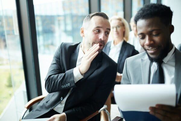 One businessman telling another businessman a secret in a meeting