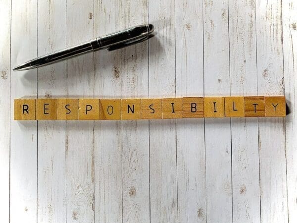 Responsibility Responsibility spelled with wooden word scramble cubes next to a balck pen