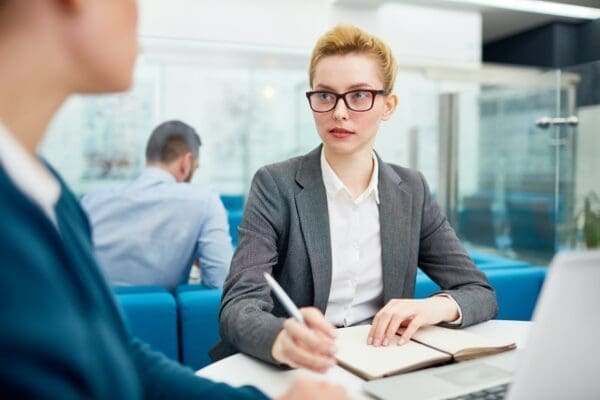 Businesswomen at an office desk talking to a male colleague