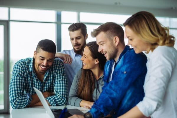 Happy team members huddled around one laptop