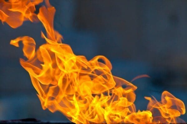 Close-up of bright orange flames against a blurred blue background