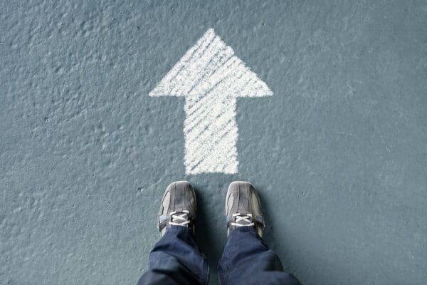 Man standing behind a forward direction arrow