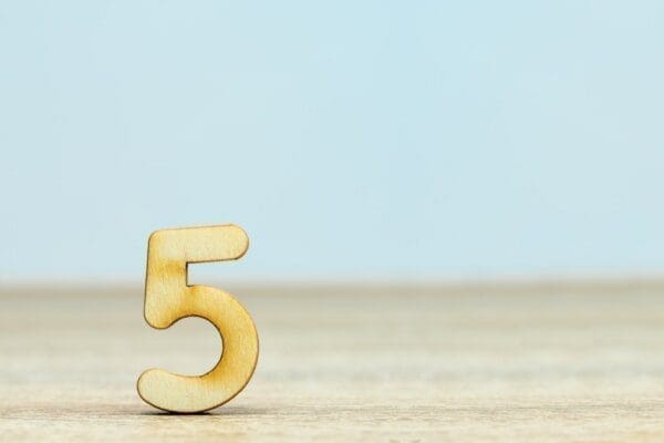 Gold number five on a beige and blue background