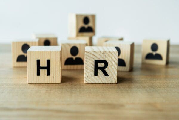 HR letters on wooden blocks with employee blocks in the background