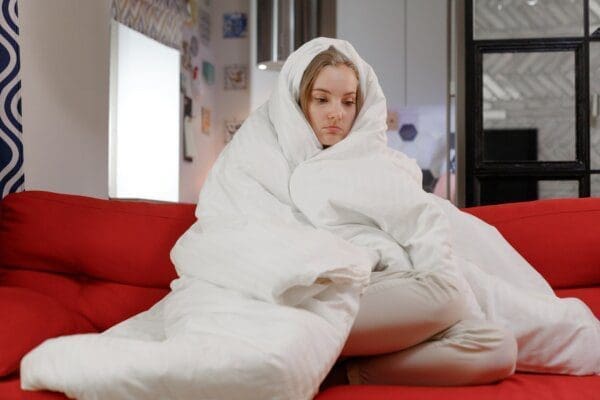 Woman under thick white blanket dealing with mental health