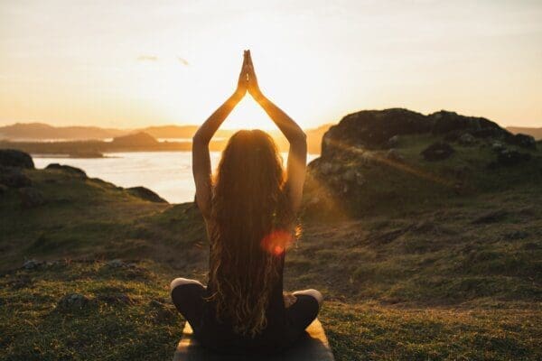 Young woman practicing yoga outdoors to improve her wellbeing