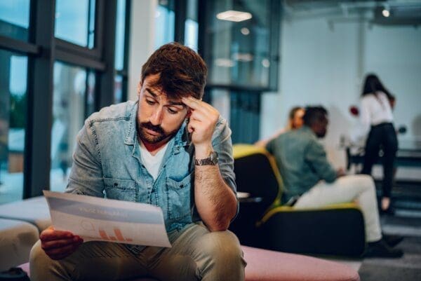 Bearded business man reading bad news while sitting in the office