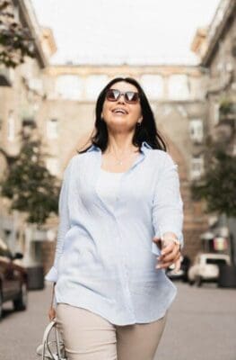 Successful confident businesswoman wearing sunglasses while walking through the street