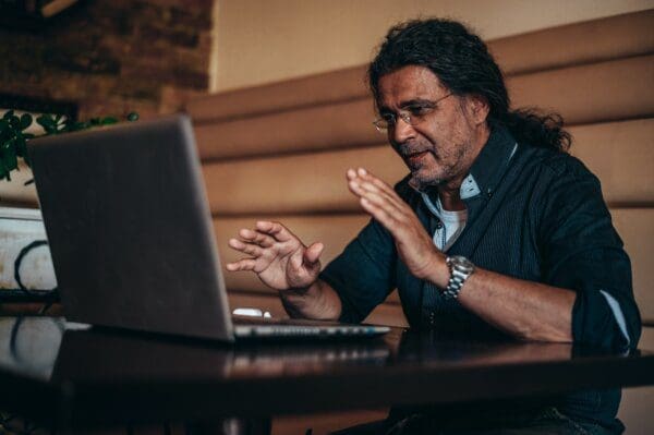 Man using his laptop for an online video call in a cafe