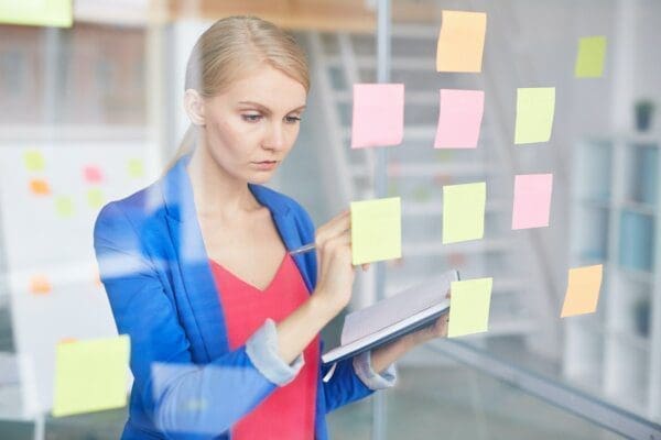 Woman writing on post it notes on a glass door