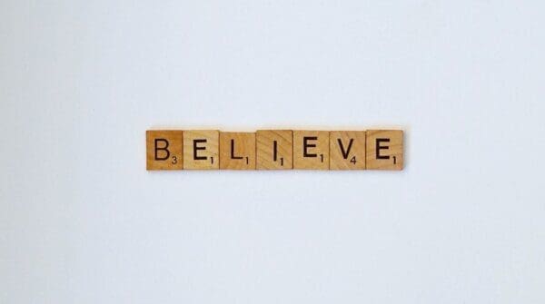 Believe spelled with wooden word scramble cubes on a white background