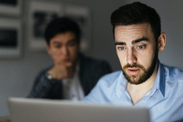 Two businessmen looking curiously at computer screen