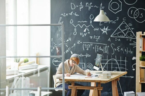 Student doing one to one training on a computer with chalkboard behind