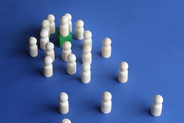 White figures in a crowd with one standing on a green podium