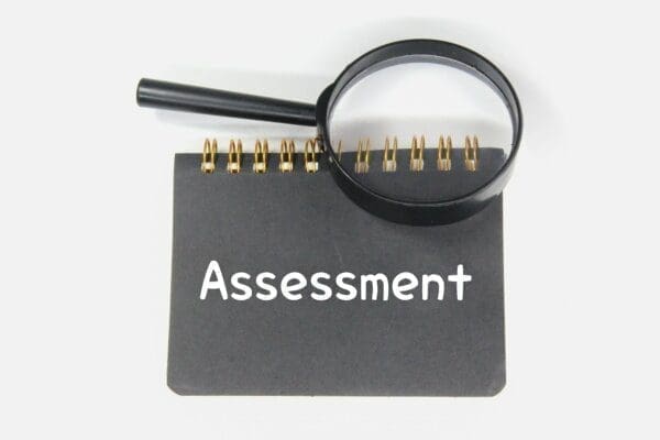 Notebook with assessment on the front and a magnifying glass