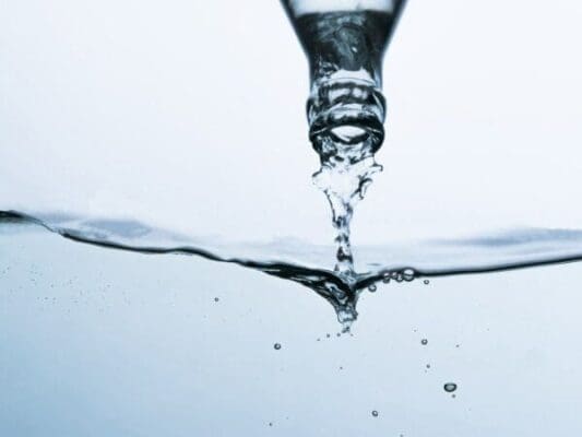 Water being poured from a bottle into a pool of water