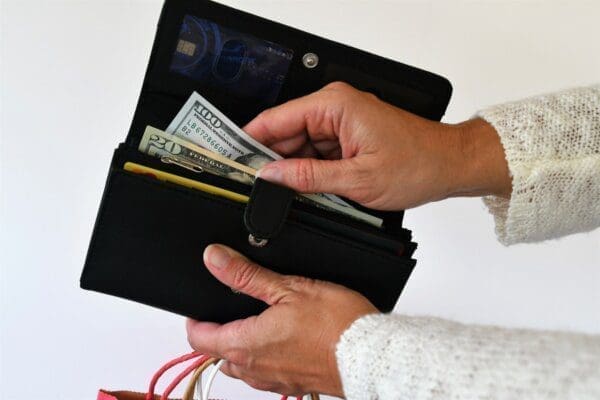 Pulling money out of a wallet while holding shopping bags to make a cash purchase