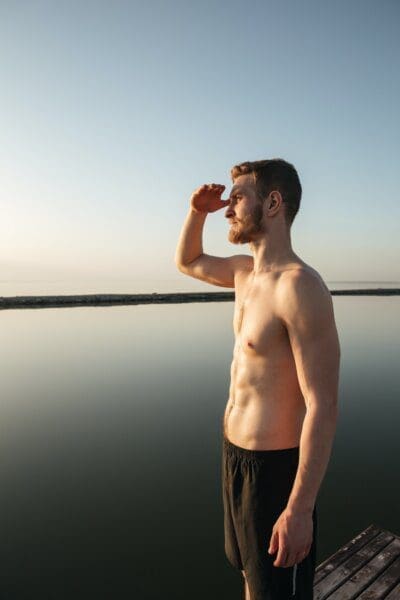 Sports man standing at the beach and looking far away