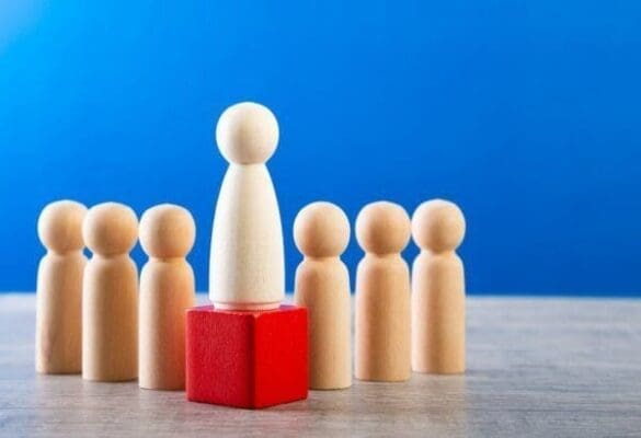 Leadership figure Wooden figure on top of block surrounded by other wooden figures