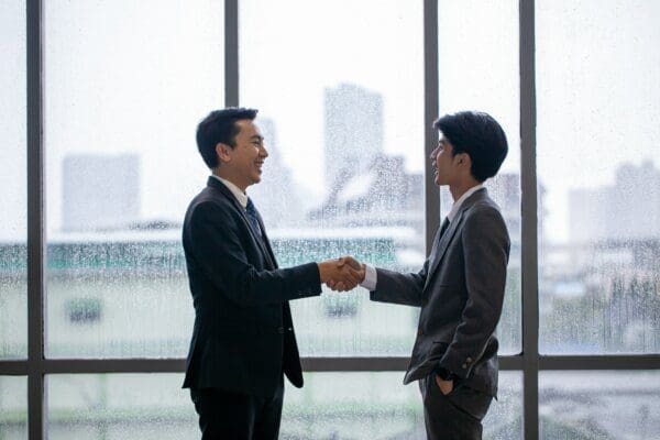 Businessman shaking hands with glass wall in the background