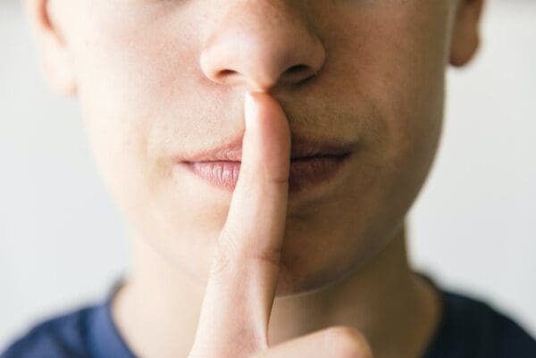 Man holding his index figure before his lips in a gesture of silence